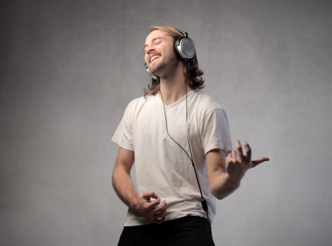 a guy playing air guitar with headphones on. wearing a white t-shirt